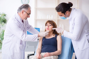 Obraz premium Two male doctors and young woman in plastic surgery concept