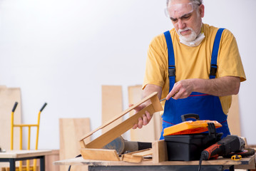 Old male carpenter working in workshop