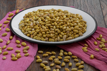 Raw yellow beans in a white metal plate on wood