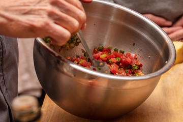 Chef preparing ingredients and teaching how to make Sushi mixing tuna and seasonings in a bowl