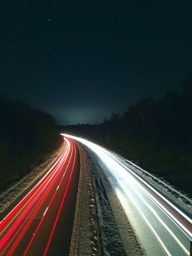 LIGHT TRAILS ON HIGHWAY AGAINST SKY AT NIGHT