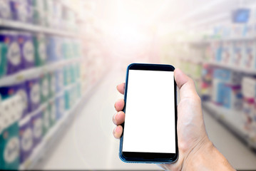 Hand of a man holding smartphone device in the blur Shopping mall background and have white copy space on screen.