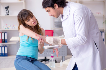 Young arm injured woman visiting young doctor traumatologist