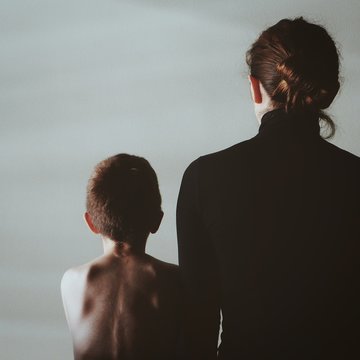 Rear View Of Mother With Shirtless Son Standing Against Sky