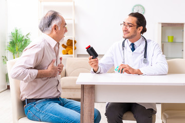 Young male doctor visiting old patient at home