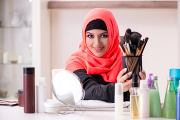 Beautiful woman in hijab applying make-up