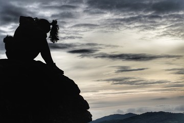 silhouette of man on top of mountainSad girl on a stone in the mountain at sunrise.