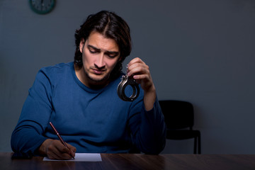 Young convict man sitting in dark room