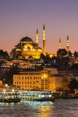 Fototapeta premium Meczet Sulejmana Wspaniałego i łodzie turystyczne o zmierzchu w Stambule, Turcja