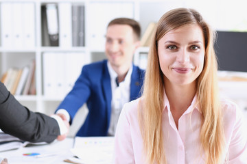 Beautiful smiling cheerful girl at workplace look in camera with colleagues group in background. White collar worker at workspace job offer modern lifestyle client visit profession train concept