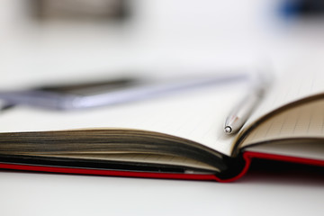 Silver pen lying on opened notebook sheet closeup in office with laptop pc on worktable. Inspector occupation for student examination or career strategy personal training course signature concept