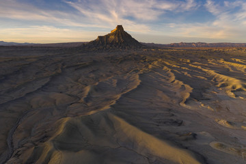 sunset over dramatic desert badlands texture with butte in distance