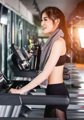 Fototapeta na wymiar Young woman lifestyle standing drinking water on treadmill exercise cardio