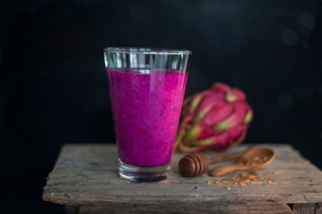 Red Dragon fruit on wooden surface, solid black background, still life shooting style.