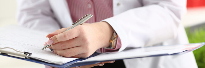 Male doctor arm hold silver pen filling patient complaints list clipped to pad. Physical exam er disease prevention ward round visitor check prescribe remedy healthy lifestyle concept