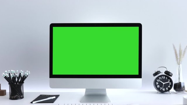 Computer desktop with mock-up green screen white background  in office, Zoom shoulder view.
