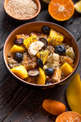 Fresh quinoa organic fruit salad in bowl on wooden  background. Helthy superfood detox concept.  Vegan/vegetarian food. Space for text. Top view