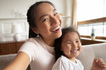 Self-portrait picture of smiling Asian mom and little daughter