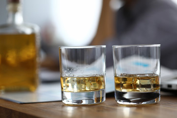 Close-up of two glassful with strong drink on wooden table. Colleagues relaxing after busy day. Employee celebrating signing contract. Business concept