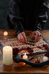 Mystic ritual with Devil's board and candles. The girl calls spirits.The mystical atmosphere of...