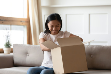 Excited asian girl unpack cardboard parcel online order