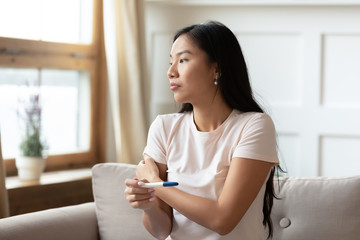 Pensive Asian woman do ovulation pregnancy test