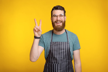 Portrait of smiling chef man showing two fingers Peace gesture