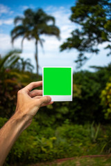 Holding Polaroid in front of scenic view(Portrait)