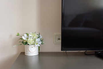Pot of white flowers on TV stand.
