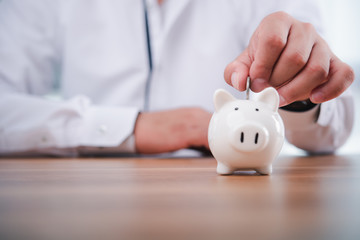 Obraz na płótnie Canvas businessman hand putting coins with piggy bank.money saving and investment concept.