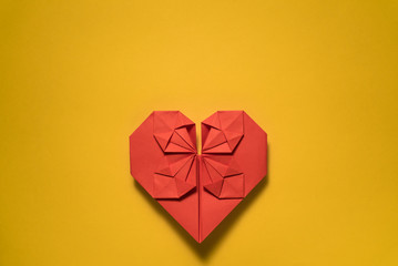 red origami paper heart on yellow background, valentines day greeting card