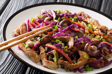 Traditional Chinese fried pork moo shu with vegetables and mushrooms close-up in a plate on the table. horizontal