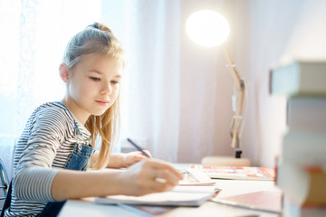 Teenage girl doing homework at table at home preparing for school test