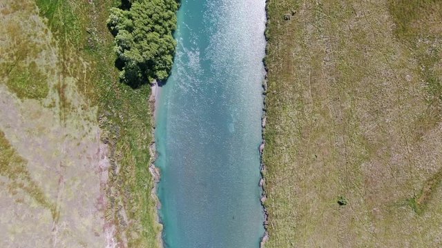 Beautiful high angle aerial drone bird's eye footage flying along crystal clear water flowing through Ahuriri River and beautiful grassland in the Canterbury Region of New Zealand's South Island.
