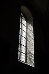 Side view of light through a Gothic stone church window among the dark background , copy space , wallpaper