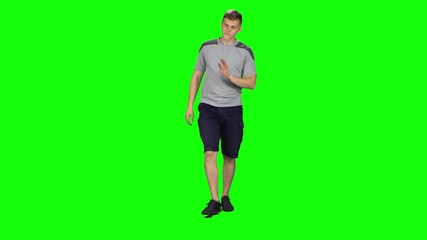 Young man walking and waves his hand on a Green Screen, Chroma Key