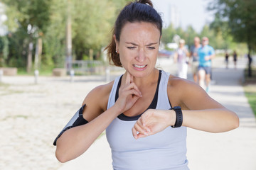 woman checking her neck pulse and looking at wristwatch