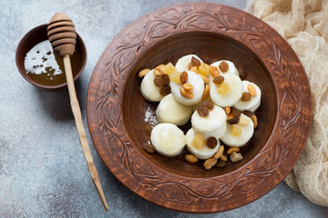 Clay plate with boiled curd dumplings or vareniki over beige stone background, studio shot