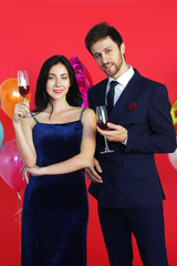 Sweet couple Love smile and spending Romantic with drinking wine in christmas time and celebrating new year eve, valentine day with colorful balloon on red background