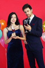 Sweet couple Love smile and spending Romantic with drinking wine in christmas time and celebrating new year eve, valentine day with colorful balloon on red background