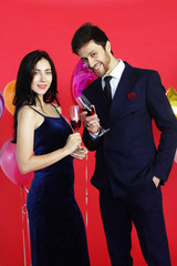 Sweet couple Love smile and spending Romantic with drinking wine in christmas time and celebrating new year eve, valentine day with colorful balloon on red background