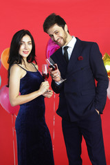 Sweet couple Love smile and spending Romantic with drinking wine in christmas time and celebrating new year eve, valentine day with colorful balloon on red background