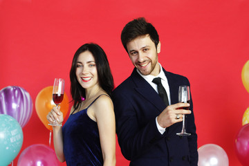 Sweet couple Love smile and spending Romantic with drinking wine in christmas time and celebrating new year eve, valentine day with colorful balloon on red background