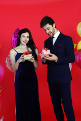 Sweet couple Love happy with surprise gift box girlfriend in christmas party, Birthday time celebration new year eve, Valentine day decoration with colorful balloon on red background