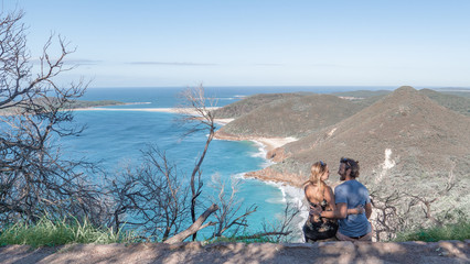 Naklejka premium Couple sitting and overlooking the ocean at Tomaree Head in Australia