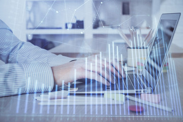 Double exposure of stock market graph with man working on laptop on background. Concept of financial analysis.