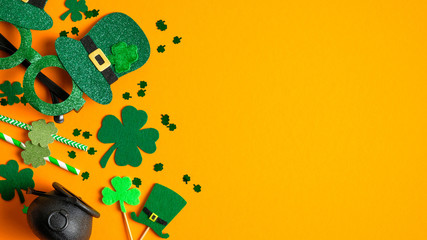 St Patricks Day frame border of Irish elf hat, glasses, pot of gold, shamrock leaf clovers on orange background with copy space. Happy St Patrick's Day concept. Greeting card template, banner mockup