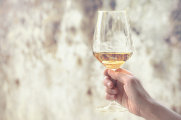 glass of wine on rusty background, female hand holding a traditional italian beverage