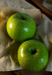 Still life of fruit, with 3 green apples on a wooden tray. Closeup and depth of field