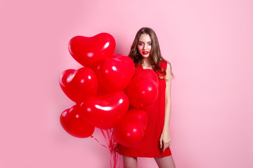 Valentine fashion girl with red heart air balloons on pink background. Birthday party